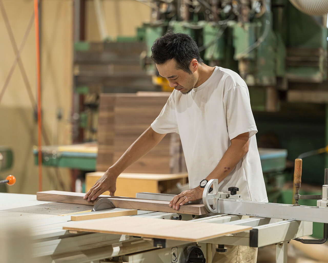 専用機械を使って木材を精密にカットする職人の集中した姿