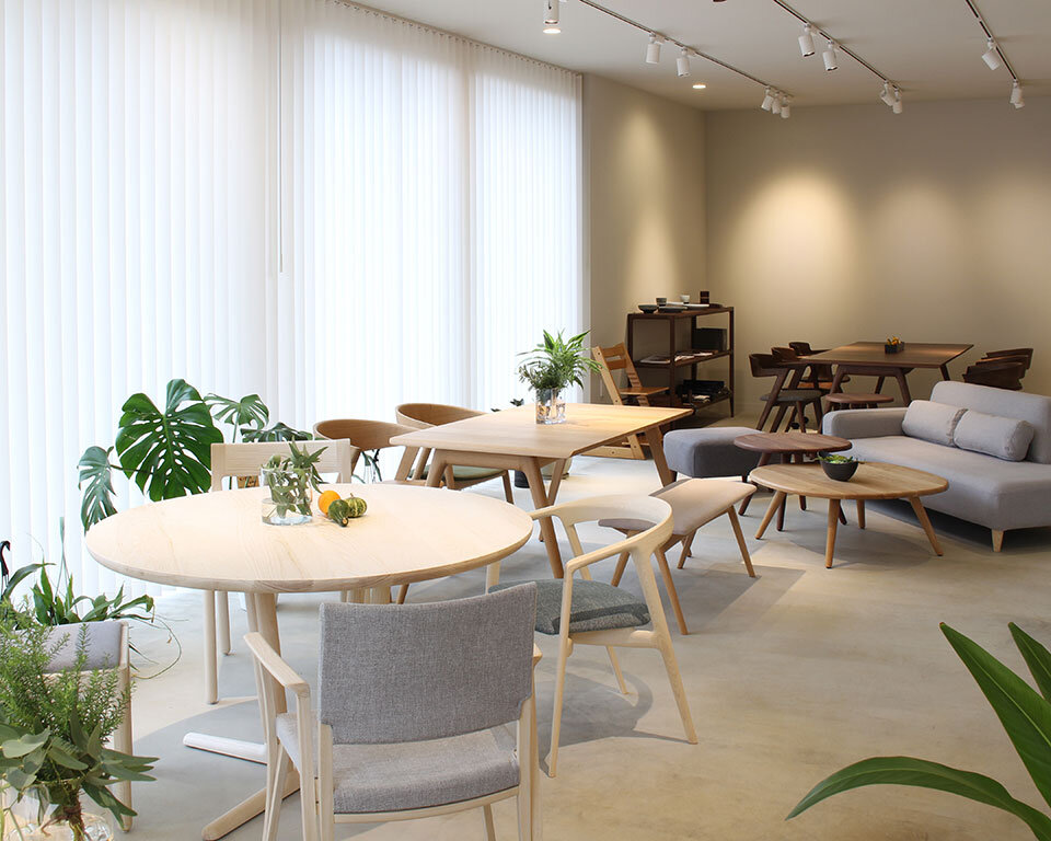 川崎市の街ノ停留所カフェスペース内観。イストクの家具と観葉植物が調和した明るい空間。