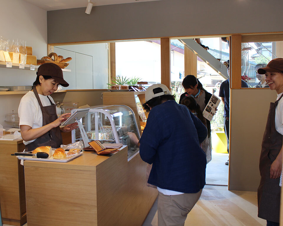街ノ停留所内の「めぐみ焼菓子店」。木の温もりを感じる店内で焼きたてパンを購入する地域の人々