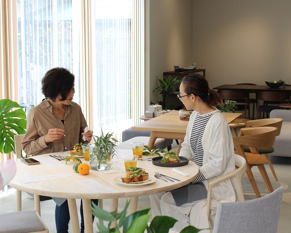 街ノ停留所カフェで食事を楽しむ女性客。イストクデザインのテーブルと椅子でくつろぐ様子。