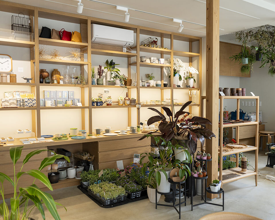 街ノ停留所内の雑貨販売コーナー。山田さんがデザインしたものや植物と木製食器が並ぶHARPシェルフが特徴的なインテリア空間。