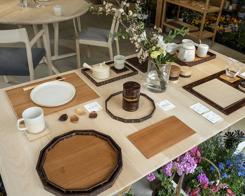 街ノ停留所での山田佳一朗デザインの木製トレイや食器の展示販売。花と木の調和が美しい空間。