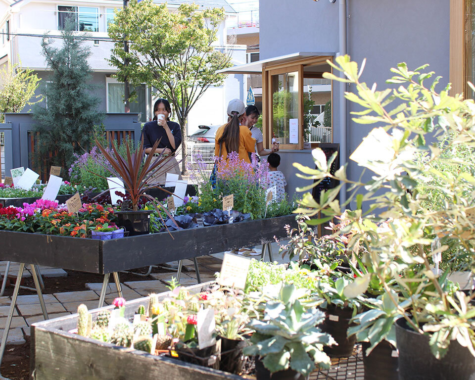 街ノ停留所の屋外店舗スペース。多彩な植物が並び、コミュニティの交流拠点として機能する様子。