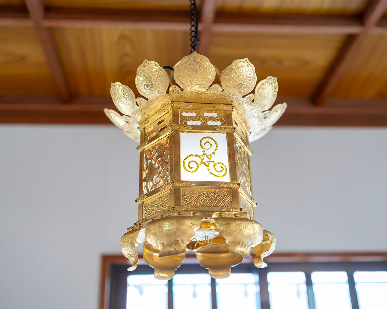 現福寺のお堂に吊るされた、奥様のペイントが施された伝統的な金色の灯籠。